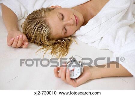 Woman sleeping holding an alarm clock View Large Photo Image Stock Image - Woman sleeping holding an alarm clock. Fotosearch