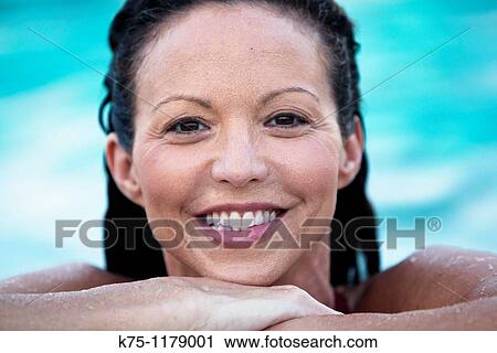 Stock Image - Woman smiling at edge of pool. Fotosearch