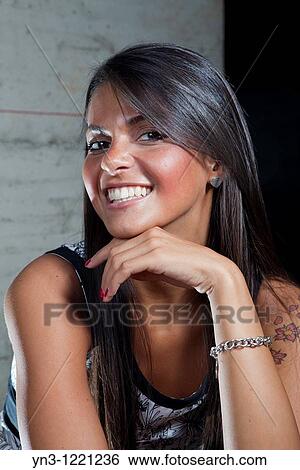 Stock Photograph - Woman smiling holding her hand under her chin. Fotosearch