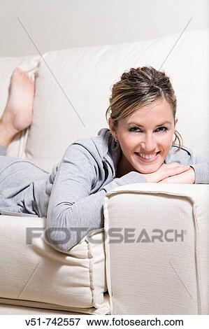 Stock Photo - Woman smiling in the couch. Fotosearch