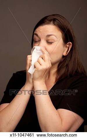 Woman sneezing into a paper handkerchief View Large Photo Image Stock Image - Woman sneezing into a paper handkerchief. Fotosearch