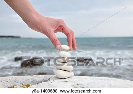 Woman stacking stones on beach View Large Photo Image Stock Photo - Woman stacking stones on beach. Fotosearch