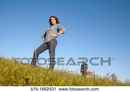 Woman standing in field with guitarist in background View Large Photo Image Stock Image - Woman standing in field with guitarist in background. Fotosearch