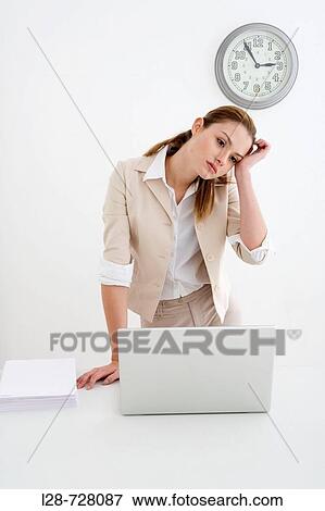 Stock Photo - Woman standing in front of the laptop, worried. Fotosearch