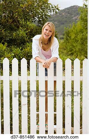 Woman standing in the garden behind the fence View Large Photo Image Stock Photograph - Woman standing in the garden behind the fence. Fotosearch