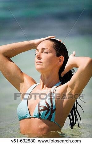 Woman standing in the sea, wit the eyes closed and hands in hair View Large Photo Image Stock Image - Woman standing in the sea, wit the eyes closed and hands in hair. Fotosearch