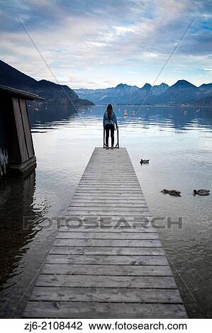 Woman standing on a pier by the Wolfgangsee lake. View Large Photo Image Stock Image - Woman standing on a pier by the Wolfgangsee lake.. Fotosearch