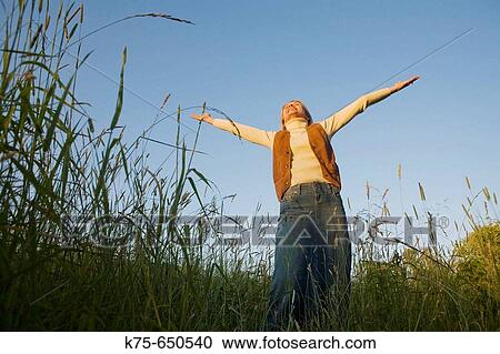 Stock Image - woman standing with arms outstretched. Fotosearch