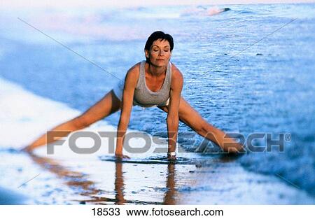 Stock Image - Woman stretching on the beach. Fotosearch