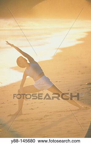 Stock Image - Woman stretching on the beach. Fotosearch