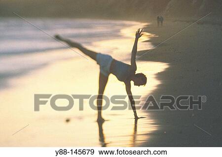Stock Photo - Woman stretching on the beach. Fotosearch