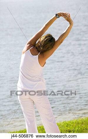 Woman stretching outdoor in front of lake View Large Photo Image Stock Photograph - Woman stretching outdoor in front of lake. Fotosearch