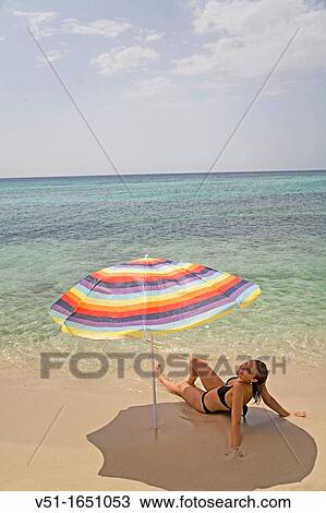 Stock Image - Woman sunbathing in a beach in Formetera, Balearic Island, Spain. Fotosearch