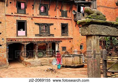 Stock Photography - Woman sweeping on a square with Newari traditional architecture, Bhaktapur, Nepal. Fotosearch