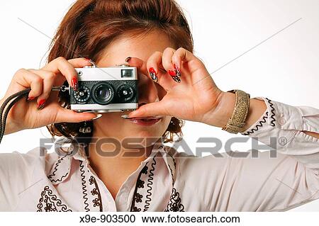 Stock Image - Woman taking a photograph with a classic camera. Fotosearch