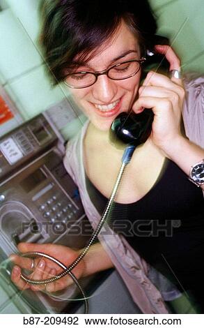 Stock Image - Woman talking on public phone. Fotosearch