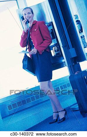 Stock Image - Woman talking on public phone. Fotosearch