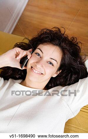 Woman talking on the phone on sofa smiling at camera View Large Photo Image Stock Image - Woman talking on the phone on sofa smiling at camera. Fotosearch