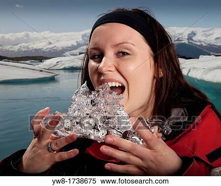 Stock Photography - Woman tasting glacial ice, Jokulsarlon Glacial Lagoon, Iceland. Fotosearch