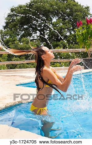 Stock Photography - Woman throwing her hair in swimming pool. Fotosearch