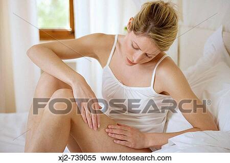 Woman touching her legs on the bed View Large Photo Image Stock Photography - Woman touching her legs on the bed. Fotosearch
