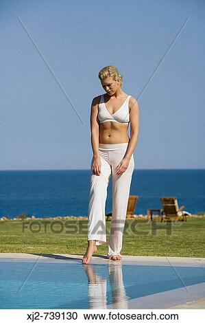 Stock Image - Woman touching the water with her foot. Fotosearch