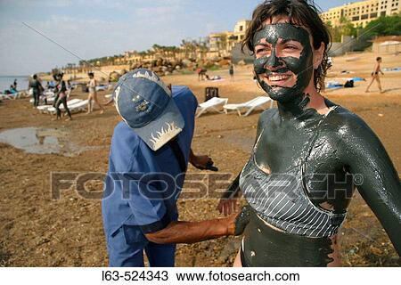 Stock Image - Woman tourist having a mud bath. Dead Sea. Jordan.. Fotosearch