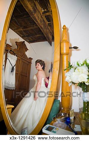 Stock Photograph - woman trying her wedding dress in front of the mirror. Fotosearch