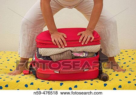 Woman trying to squeeze her packed travel case shut. View Large Photo Image Stock Photo - Woman trying to squeeze her packed travel case shut.. Fotosearch