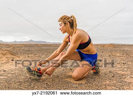 Stock Image - Woman tying her shoe laces. Fuerteventura, Canary Islands, Spain, Europe.. Fotosearch