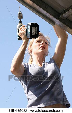 Woman using a power drill on roof View Large Photo Image Stock Image - Woman using a power drill on roof. Fotosearch