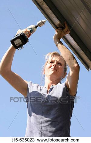 Woman using a power drill on roof View Large Photo Image Stock Image - Woman using a power drill on roof. Fotosearch