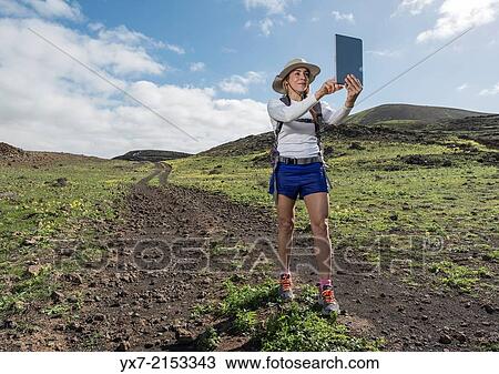 Stock Image - Woman using a Tablet at Timanfaya National Park, Lanzarote, Canary Islands, Spain.. Fotosearch