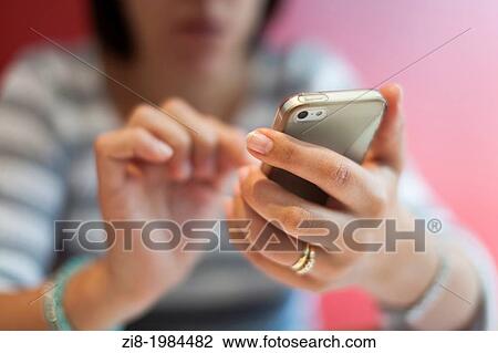 Stock Image - Woman using a touch screen mobile phone-selective focus.. Fotosearch