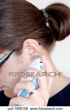 Woman using an ear thermometer View Large Photo Image Stock Photo - Woman using an ear thermometer. Fotosearch