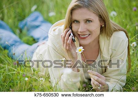 Stock Image - woman using cell phone in meadow. Fotosearch