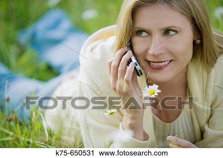 Stock Image - woman using cell phone in meadow. Fotosearch