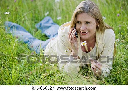 Stock Photo - woman using cell phone in meadow. Fotosearch