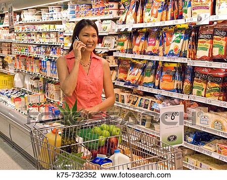 Woman using cell phone in supermarket View Large Photo Image Stock Image - Woman using cell phone in supermarket. Fotosearch