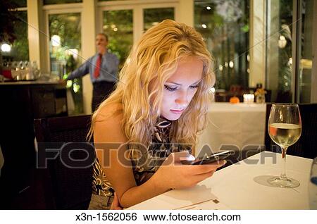 Woman using iPhone in upscale New York restaurant View Large Photo Image Stock Photograph - Woman using iPhone in upscale New York restaurant. Fotosearch
