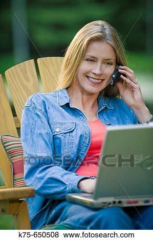 Stock Photo - woman using laptop and cell phone outdoors. Fotosearch