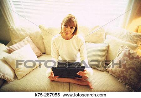 Woman using laptop in her living room View Large Photo Image Stock Photography - Woman using laptop in her living room. Fotosearch