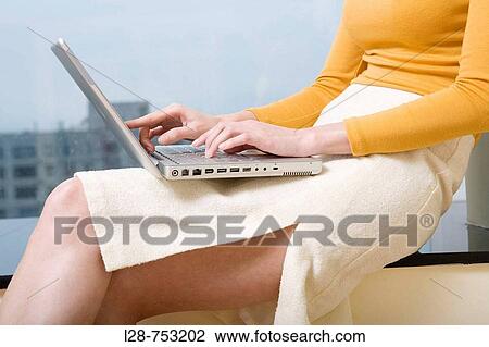 Stock Image - Woman using laptop near window, side view. Fotosearch