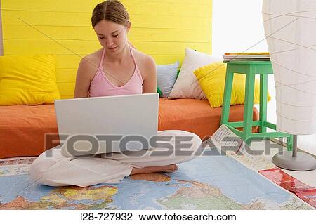 Stock Image - woman using laptop, sitting on the world map. Fotosearch