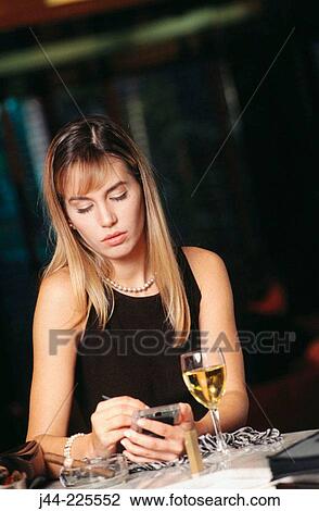 Stock Image - Woman using palm pilot in a bar. Fotosearch