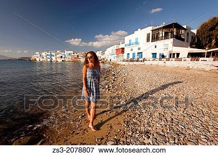 Woman walking at the beach in Little Venice district, Mykonos, Cyclades Islands, Greek Islands, Greece, Europe. View Large Photo Image Stock Photo - Woman walking at the beach in Little Venice district, Mykonos, Cyclades Islands, Greek Islands, Greece, Europe.. Fotosearch