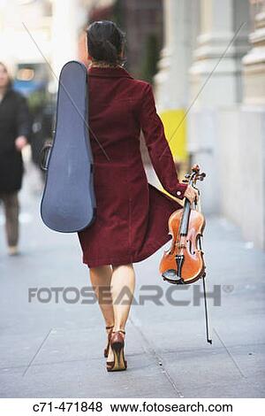 Woman walking Downtreet with back to camera holding violin and violin case View Large Photo Image Stock Photo - Woman walking Downtreet with back to camera holding violin and violin case. Fotosearch