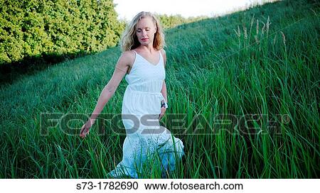 Stock Image - Woman walking in field. Fotosearch