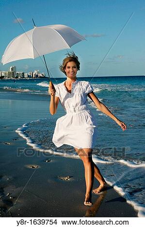 Picture - Woman walking next to seaside. Fotosearch