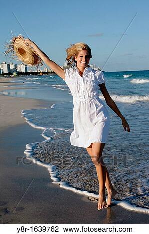 Stock Image - Woman walking next to seaside. Fotosearch